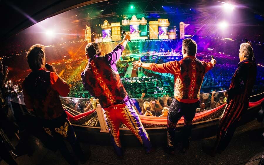 The Toppers waving to the crowd from a stage among the audience