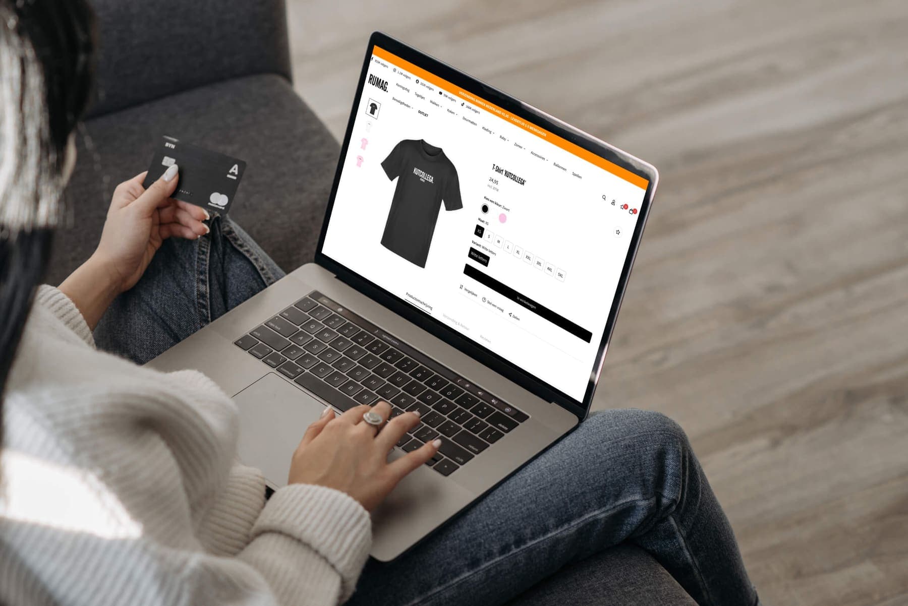 Someone holding a bank card in front of a laptop with the store's product page open.
