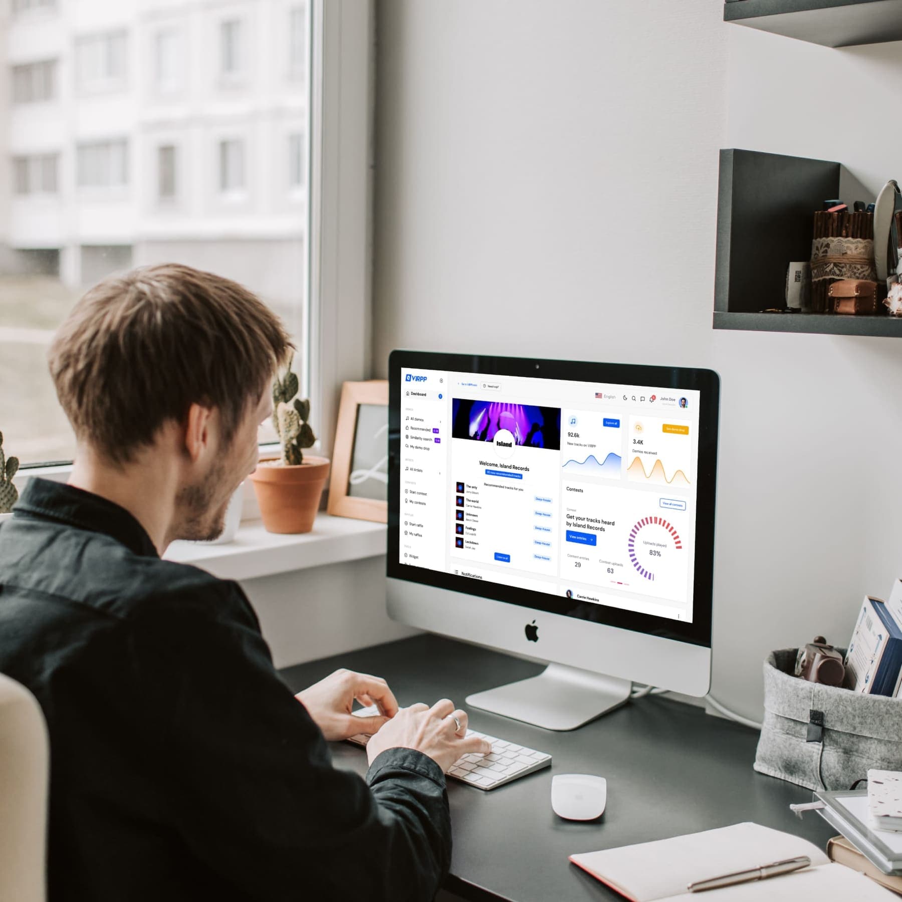 Someone working at an iMac with VIRPP's label dashboard open: recommended tracks, the number of new demos and a running contest.