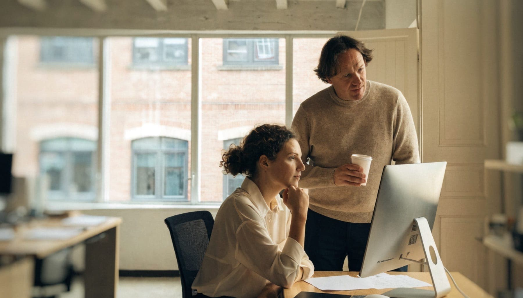 A sales employee reviews a draft on her screen before approving it