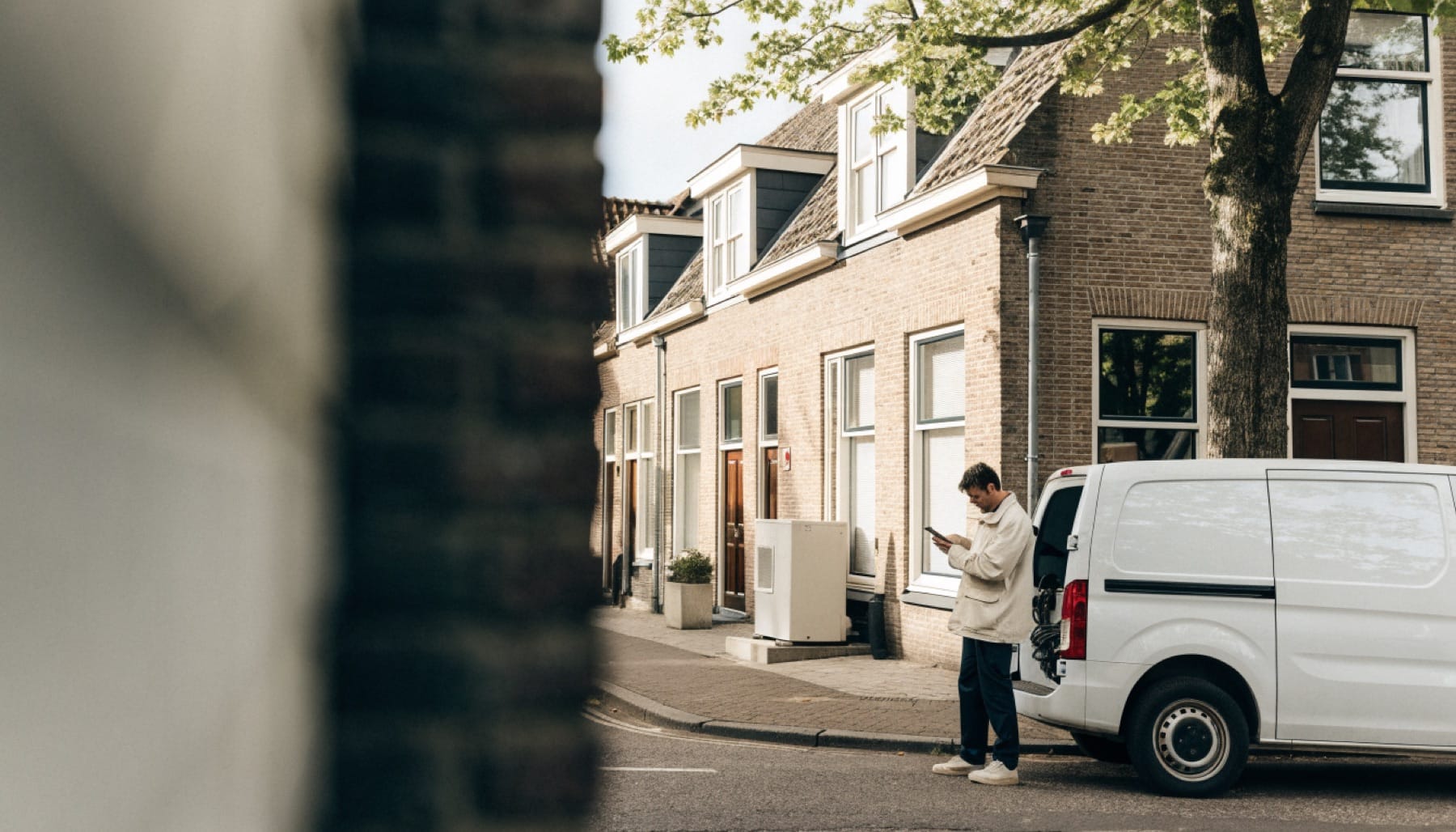 A technician wraps up a job by his van, next to a newly installed heat pump